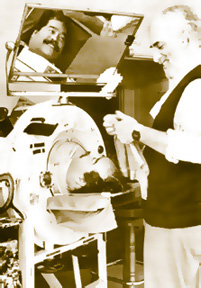 Photo of Ed Roberts in the iron lung he slept in. To his right is his long-time friend and attendant, Jonathan Gold.