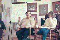 photo of two people seated by an easel, taking part in an active discussion. They don't LOOK crazy.