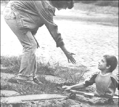 Photo of a kid, amputated at waist, on his scateboard, being offered the helping hand.